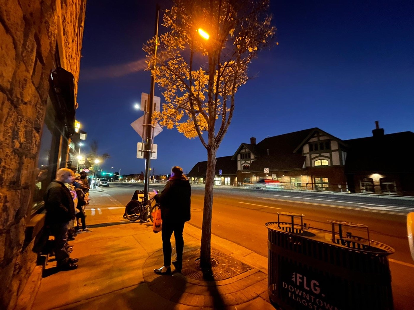 A tour group on the sidewalk with the Flagstaff train depot in view
